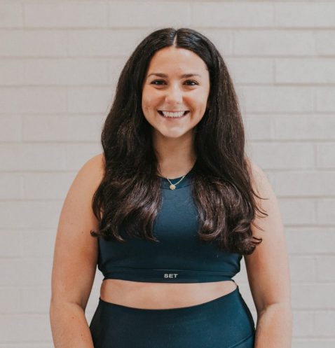 A woman standing in front of a brick wall.