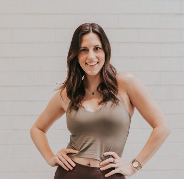 A woman standing in front of a white wall.
