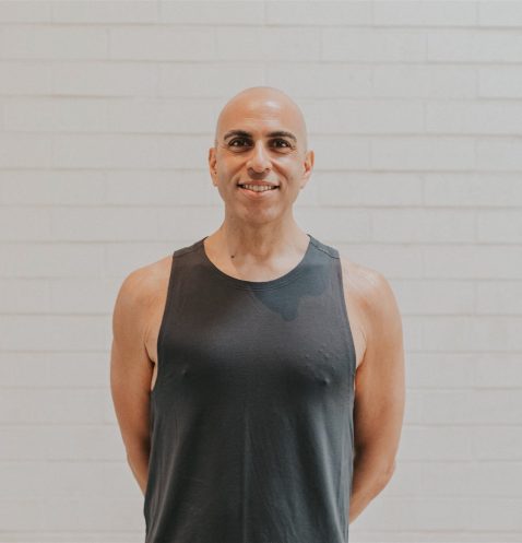 A man in black shirt standing next to wall.