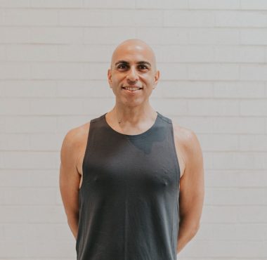 A man in black shirt standing next to wall.