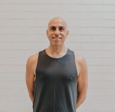 A man in black shirt standing next to wall.