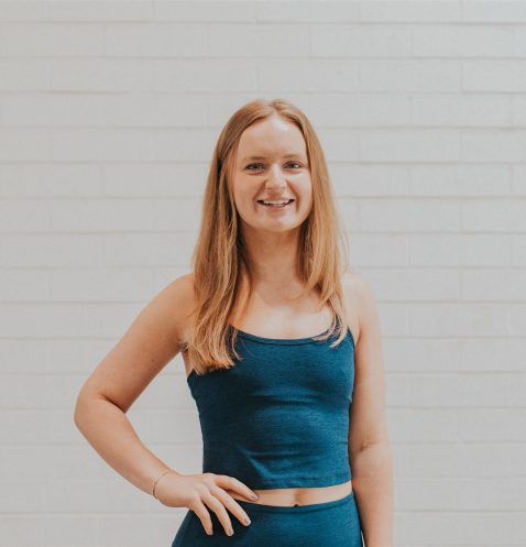 A woman standing in front of a white wall.