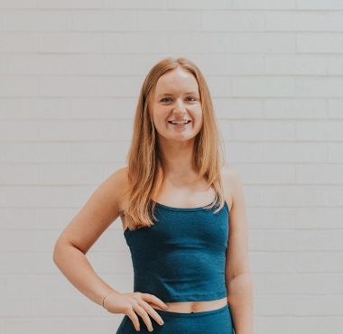 A woman standing in front of a white wall.