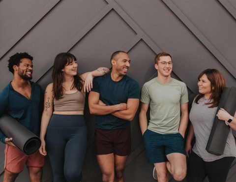 Group of friends with yoga mats smiling.