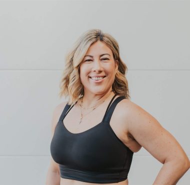 Smiling woman in workout attire posing confidently.