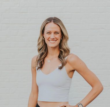 A woman standing in front of a white wall.