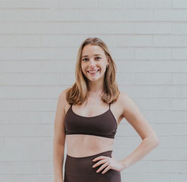 Woman in athletic wear against brick wall.