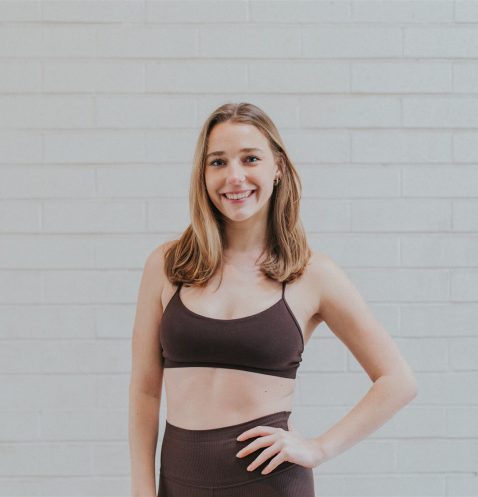 Woman in athletic wear against brick wall.