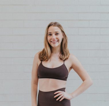 Woman in athletic wear against brick wall.