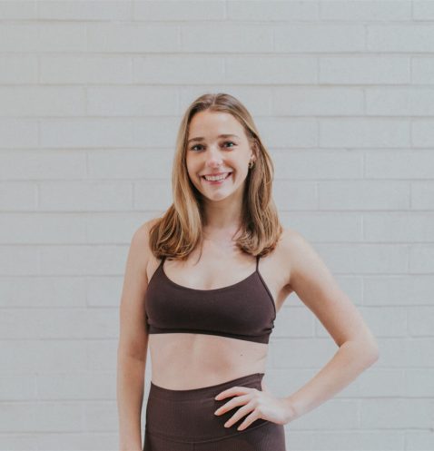 Woman in athletic wear against brick wall.