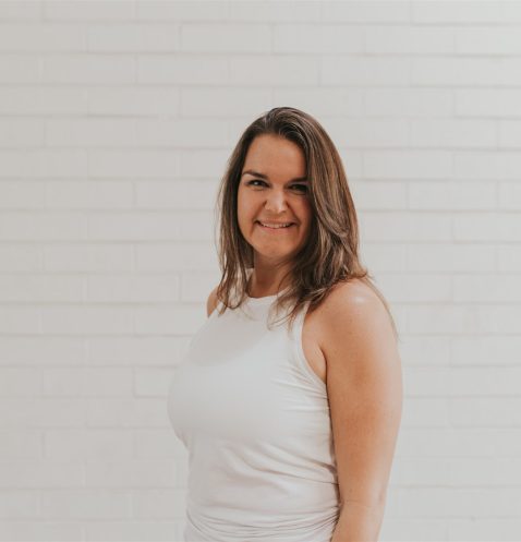 A woman standing in front of a white wall.