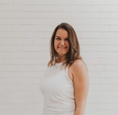 A woman standing in front of a white wall.