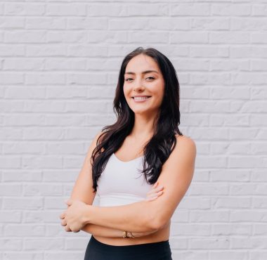 Woman smiling in front of brick wall.