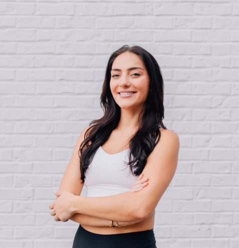 Woman smiling in front of brick wall.