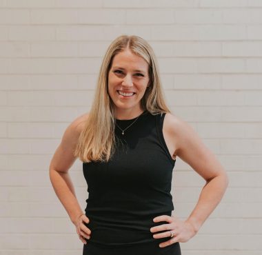 A woman in black dress standing with hands on hips.