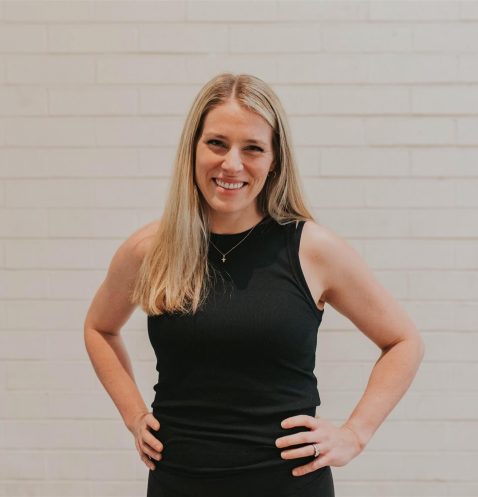 A woman in black dress standing with hands on hips.