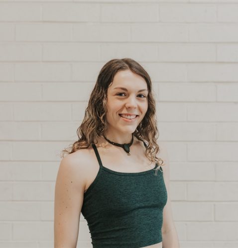 A woman standing in front of a white wall.