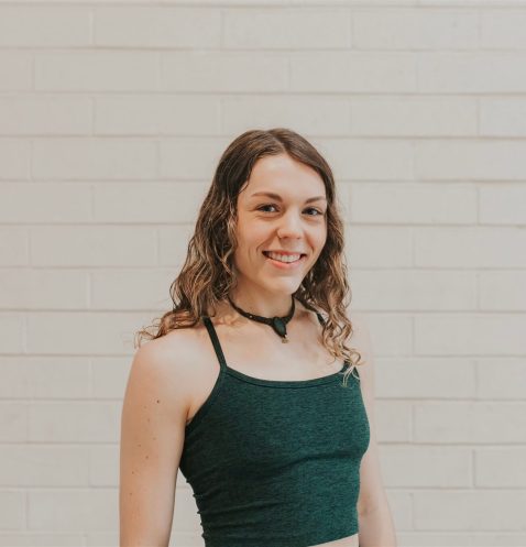 A woman standing in front of a white wall.