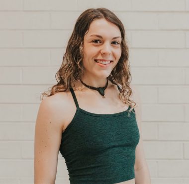 A woman standing in front of a brick wall.