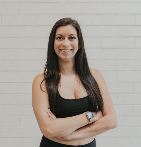 A woman standing in front of a white wall.