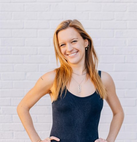 Smiling woman in front of white brick wall.