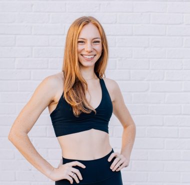 Smiling woman in athletic wear, white background.