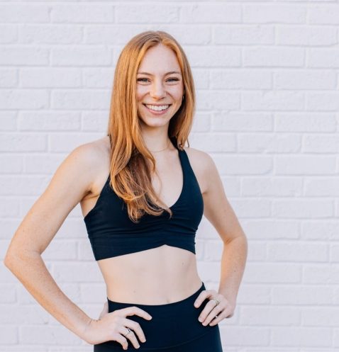 Smiling woman in athletic wear, white background.