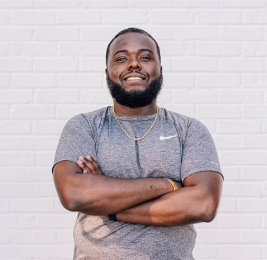 Man smiling with arms crossed against wall.