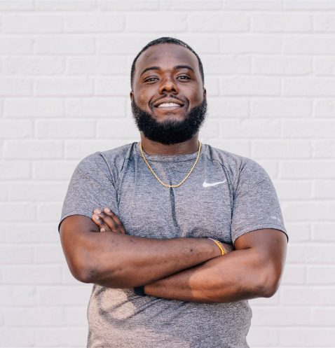 Man smiling with arms crossed against wall.