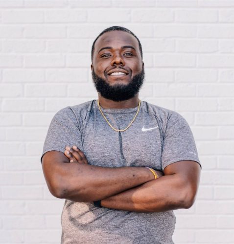 Man smiling with arms crossed against wall.
